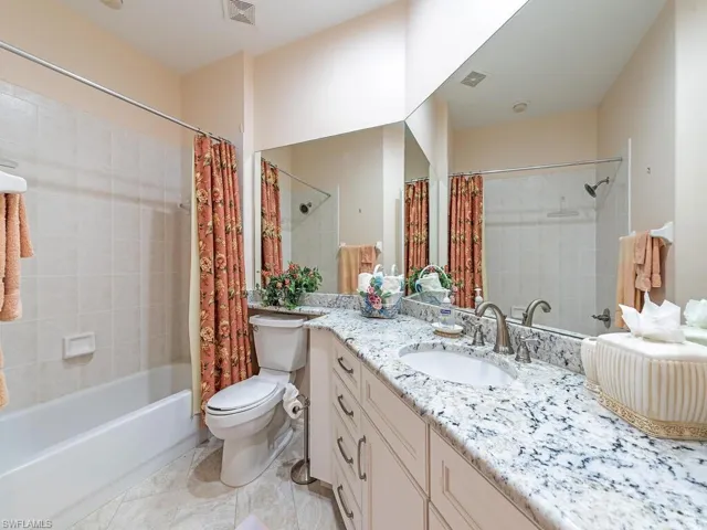 Full bathroom with vanity, shower / bath combo with shower curtain, and toilet