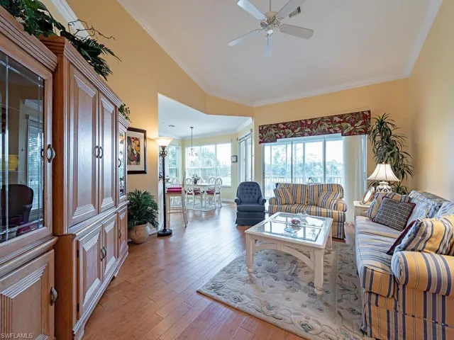 Living room featuring light wood-type flooring, ornamental molding, and ceiling fan