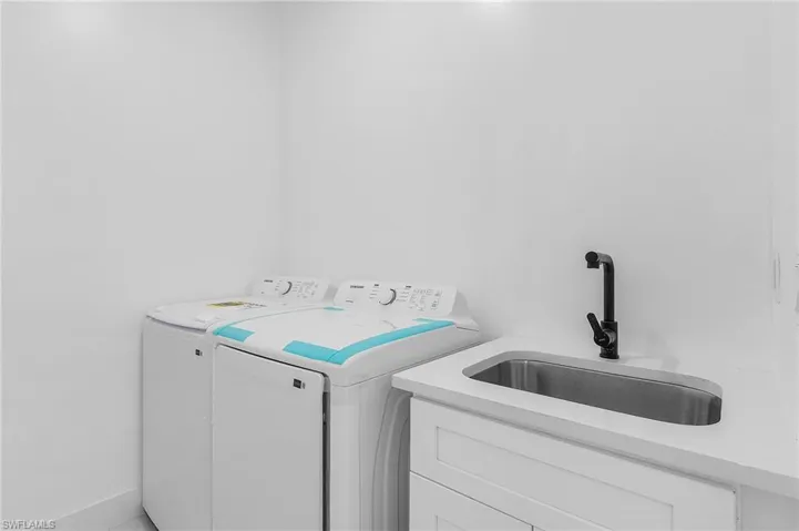 Clothes washing area with cabinets, sink, and independent washer and dryer