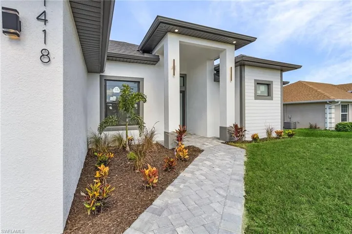 Property entrance with central AC unit and a lawn
