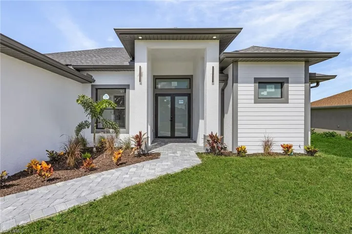 View of exterior entry featuring a yard and french doors