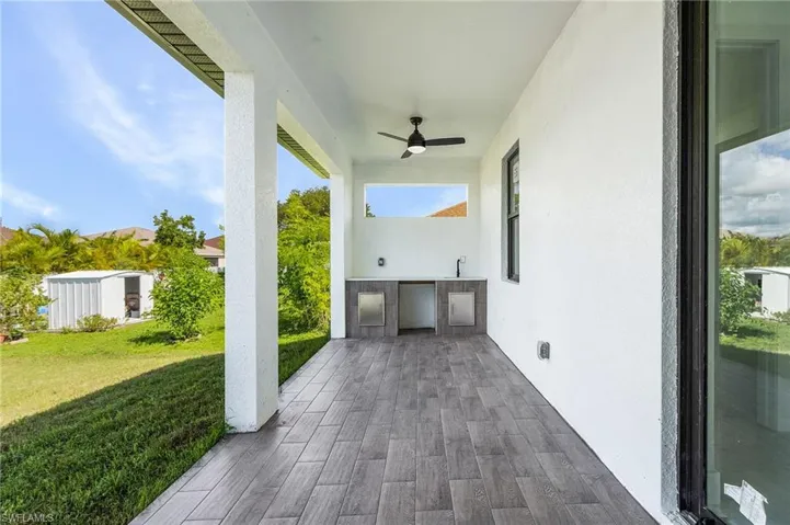 View of patio with ceiling fan, an outdoor kitchen, and a storage unit
