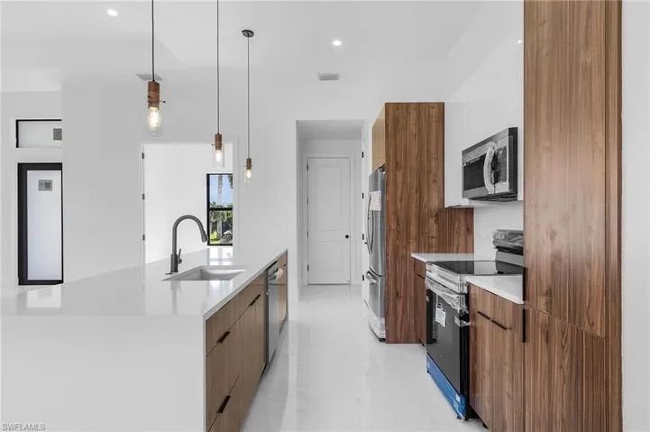 Kitchen with a center island with sink, hanging light fixtures, stainless steel appliances, and sink