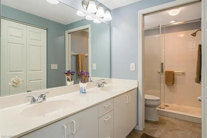 Full bath featuring double vanity and a stall shower