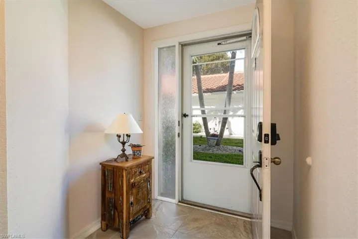 Doorway featuring baseboards and a textured wall