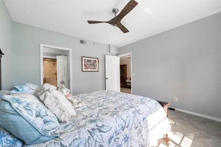 Bedroom with ceiling fan, ensuite bath, and ornamental molding