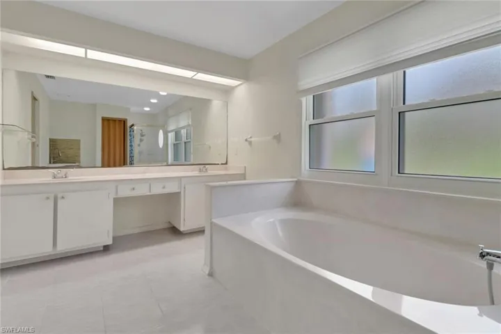 Bathroom featuring a sink, double vanity, a stall shower, and a garden tub