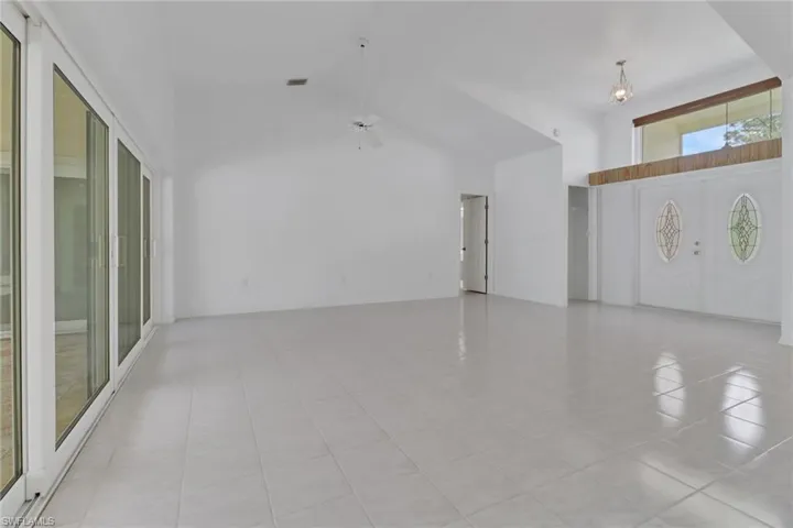 Spare room with a high ceiling, light tile patterned floors, a ceiling fan, and visible vents