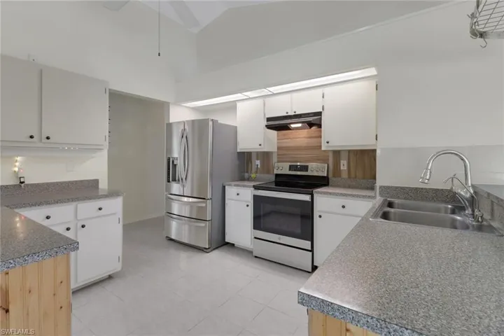 Kitchen featuring appliances with stainless steel finishes, a sink, white cabinetry, and under cabinet range hood
