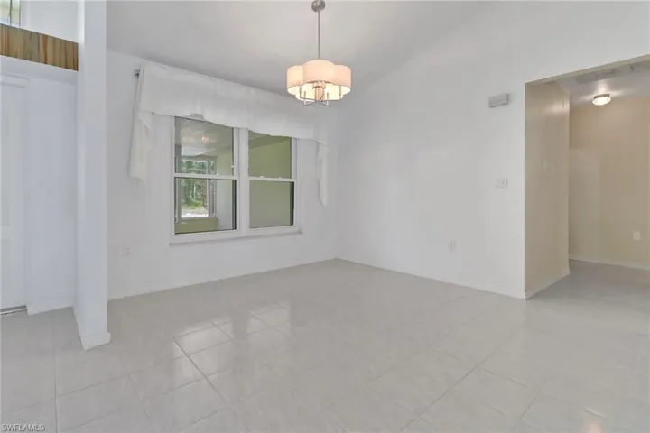 Spare room featuring baseboards and an inviting chandelier