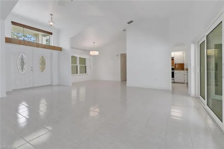 Foyer with light tile patterned floors, visible vents, arched walkways, a notable chandelier, and high vaulted ceiling