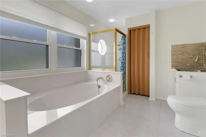 Full bathroom featuring a sink, toilet, tile patterned floors, a stall shower, and a garden tub