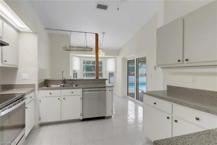 Kitchen featuring visible vents, a sink, appliances with stainless steel finishes, white cabinetry, and vaulted ceiling