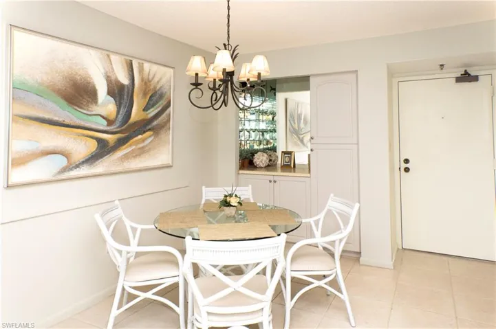 Dining space with light tile patterned flooring and a notable chandelier