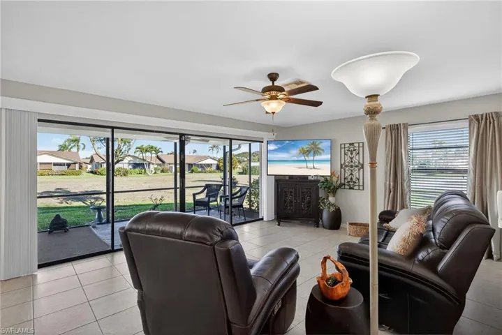 Living room with a ceiling fan and light tile patterned floors