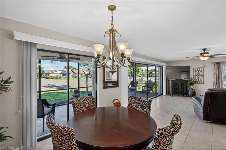 Dining room featuring a ceiling fan, a chandelier, light tile patterned floors, and plenty of natural light
