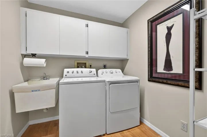 Laundry area with light wood finished floors, washer and dryer, and cabinet space