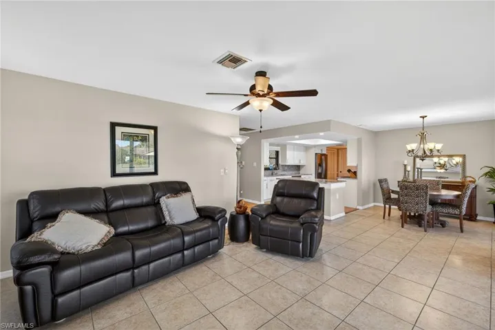 Living room with light tile patterned flooring, a ceiling fan, and a chandelier