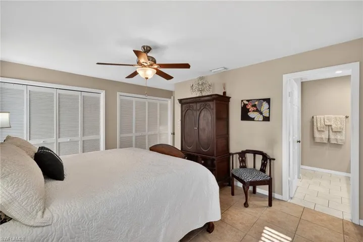 Bedroom with two closets, light tile patterned flooring, and a ceiling fan
