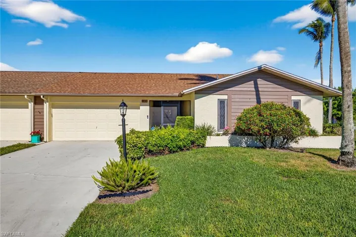 Ranch-style house with concrete driveway, roof with shingles, a front lawn, an attached garage, and stucco siding