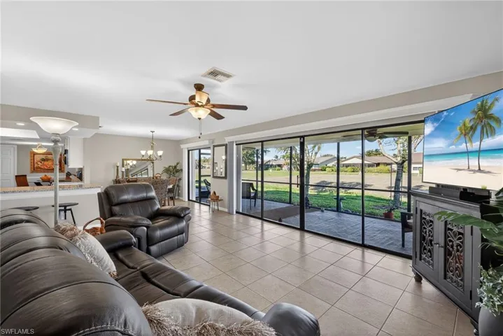 Living area featuring light tile patterned flooring, a ceiling fan, and a chandelier