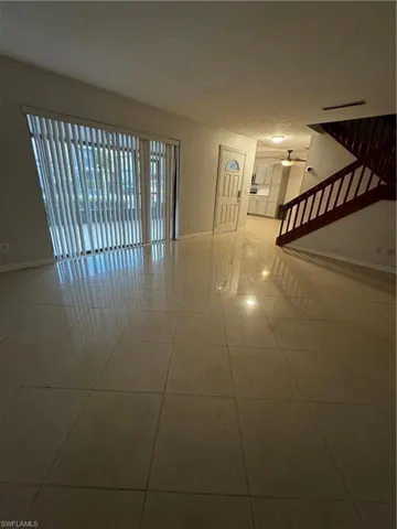 Empty room with ceiling fan, a textured ceiling, and light tile patterned floors