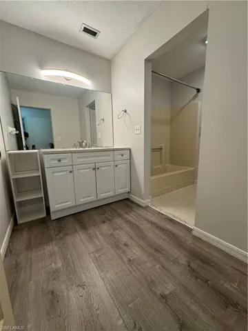 Bathroom featuring wood-type flooring, vanity, a shower, and a textured ceiling