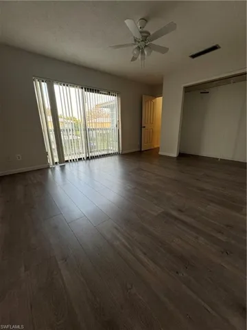 Unfurnished bedroom with ceiling fan, a closet, dark wood-type flooring, access to exterior, and a textured ceiling