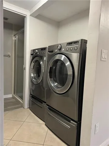 Laundry area featuring light tile patterned floors and washer and dryer