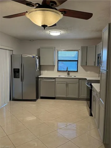 Kitchen featuring range, refrigerator, sink, light tile patterned flooring, and dishwasher
