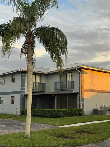 Back of property featuring cooling unit, a balcony, and a lawn