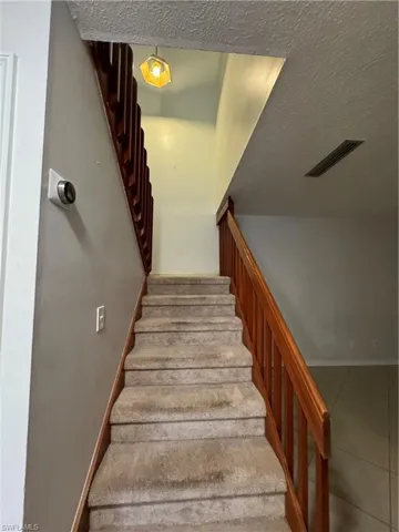 Stairs with a textured ceiling and tile patterned flooring