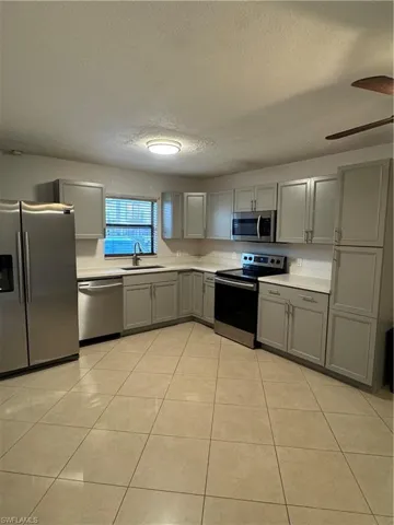 Kitchen featuring sink, gray cabinetry, range, fridge, and dishwasher