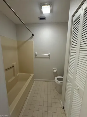 Bathroom with shower / bath combination, tile patterned flooring, and toilet