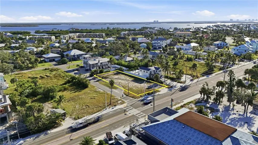Aerial perspective of suburban area featuring property parcel outlined and a large body of water - Virtually Edited Image