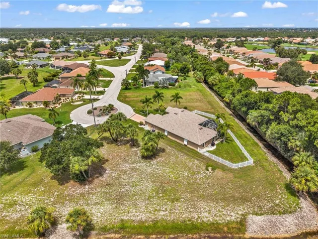 Spacious property featuring a single-story home with a screened lanai and pool, surrounded by mature palm trees