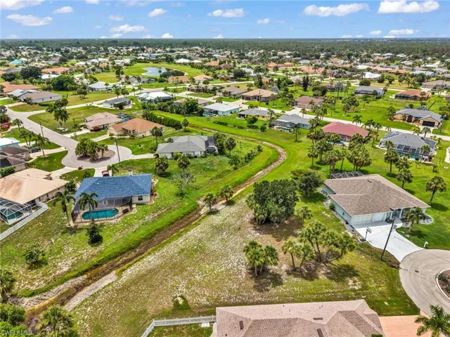Aerial perspective showcasing a residential community with numerous single-story homes, mature palm trees, and verdant landscaping