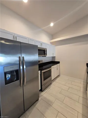 Kitchen featuring stainless steel appliances, dark countertops, recessed lighting, and white cabinets