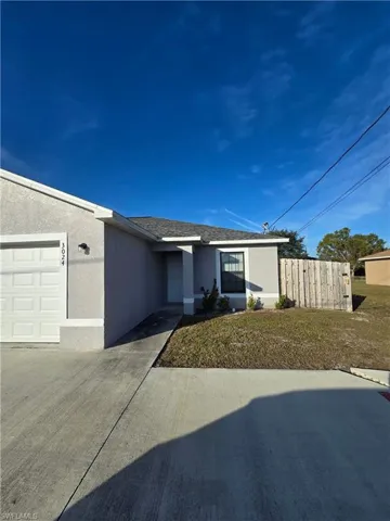 Duplex house with stucco siding and a front yard