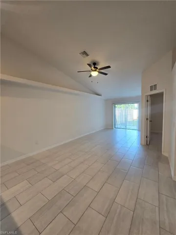 Unfurnished room with a ceiling fan, vaulted ceiling, and wood tiled floors