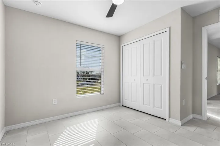 Unfurnished bedroom with ceiling fan, a closet, and light tile patterned floors