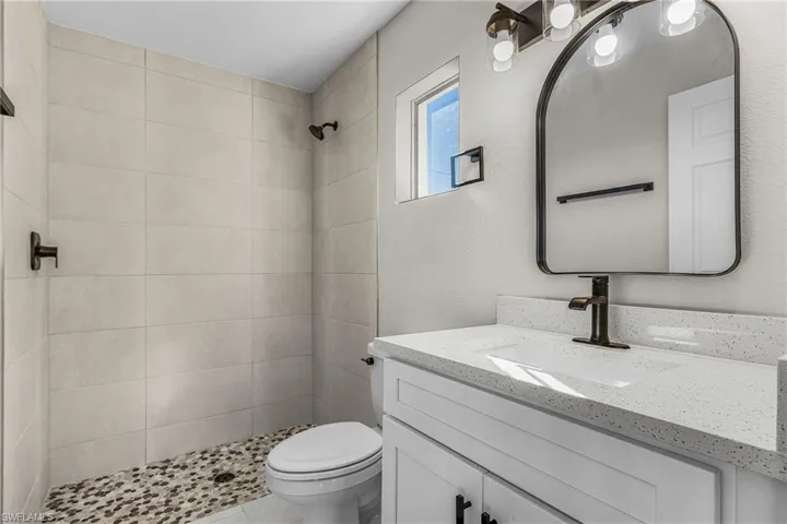 Bathroom with vanity, a stall shower, and a textured wall