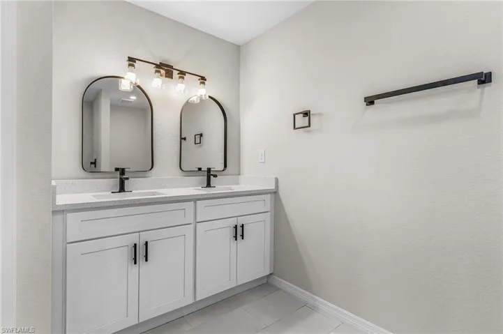 Full bath with double vanity and light tile patterned floors