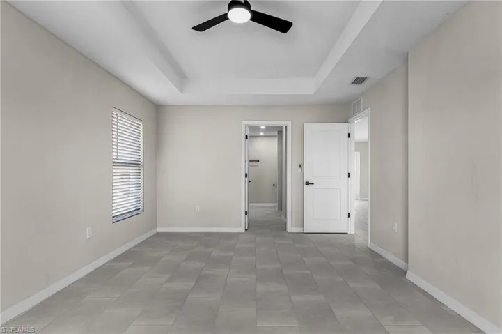 Unfurnished bedroom featuring a ceiling fan and a raised ceiling