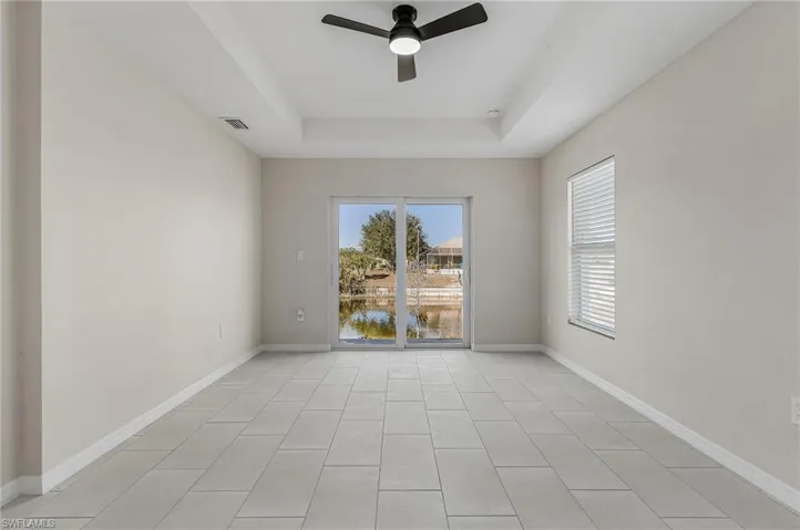 Empty room with a raised ceiling, a ceiling fan, and a water view