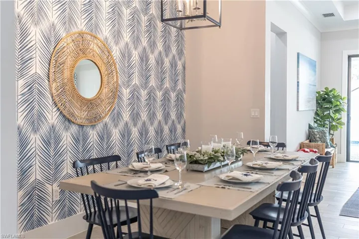 Dining space featuring an accent wall, ornamental molding, light wood finished floors, and wallpapered walls