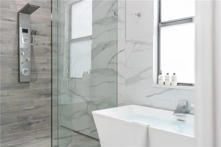 Full bath featuring a marble finish shower and a freestanding bath