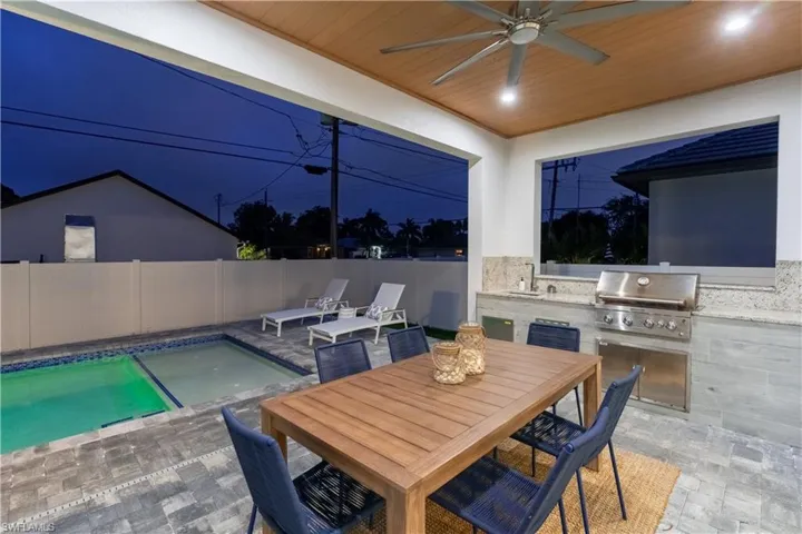 Fenced backyard featuring a patio area, an outdoor kitchen, a ceiling fan, and outdoor dining area