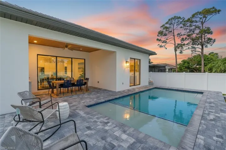Pool at dusk with a patio area and outdoor dining space