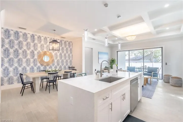 Kitchen with an accent wall, wallpapered walls, white cabinetry, light stone countertops, and coffered ceiling